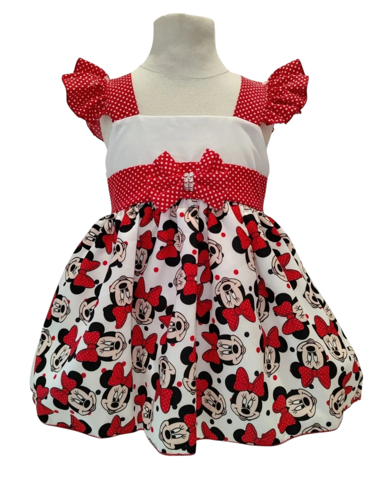 Peques girls' white dress with red polka dot flutter sleeves and Minnie Mouse print skirt. Features a rhinestone bow accent.